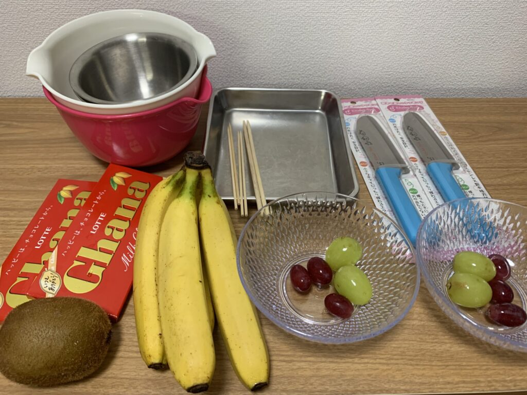 チョコバナナを作るための材料たち。チョコ、バナナのほかに家にあった果物も用意しました。
道具は、湯煎用のボールとお湯をはるための少し大きなボール、果物を刺すための串や割り箸、作ったものをおくためのバット(なければ、クッキングシートでも良いそうです)です。
あとは、トッピング用のアラザンなどもあると子供達喜びます。スーパーの製菓コーナーにあります。
